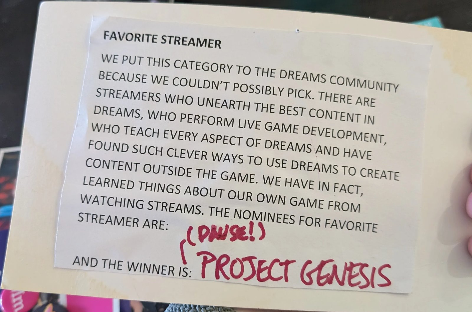 The Impys presenter card for Favourite Streamer. The printed text says the category was put to the Dreams community and the team learned things about their own game from watching streams. Handwritten in red: pause, and the winner is Project Genesis